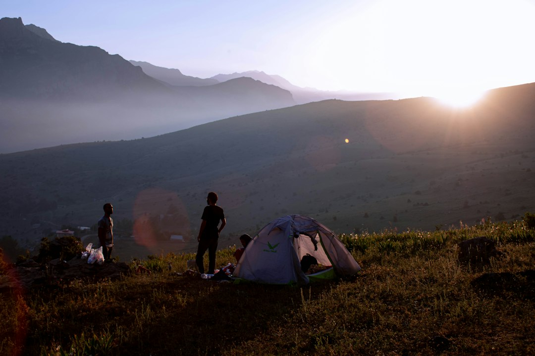 a-group-of-people-standing-around-a-tent-on-top-of-a-hill-ybenx-obvaw